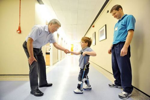 Picture of 6 year old Aiden Kennedy using his reciprocal gait walking device to walk